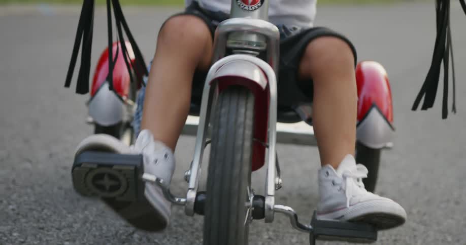 Child pedals a tricycle on a road