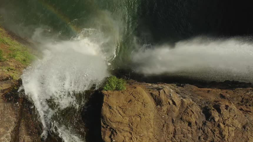 Water falls off the side of a stone cliff