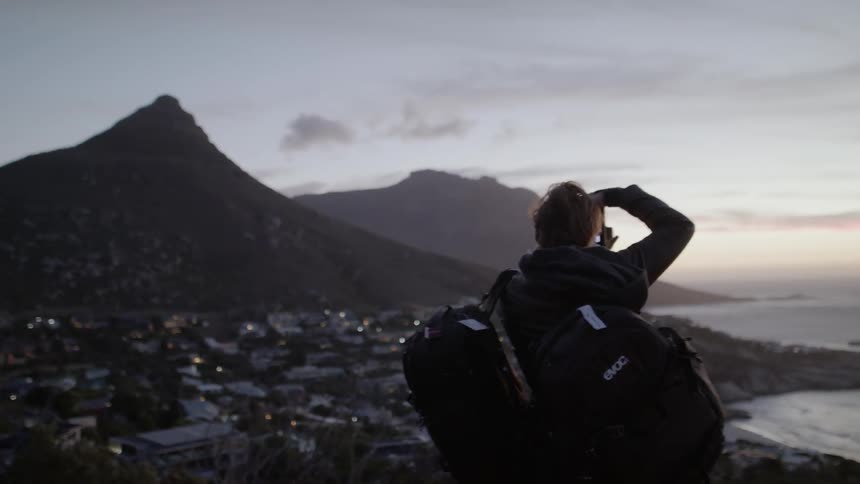 Woman with a backpack takes a photo of the lake under a cloudy sky
