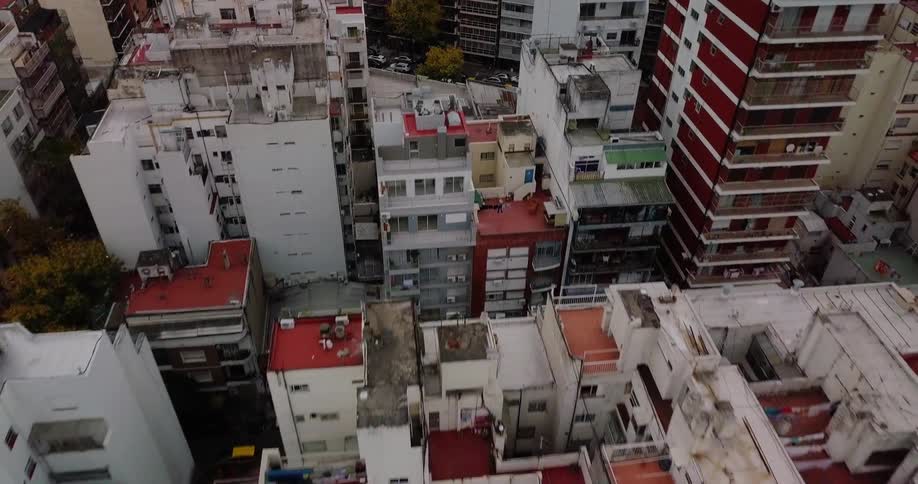 Cars drive down a busy city street next to skyscrapers