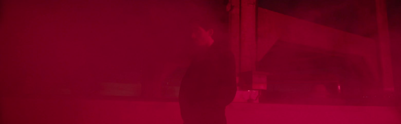 A man walks through smoke or fog at night