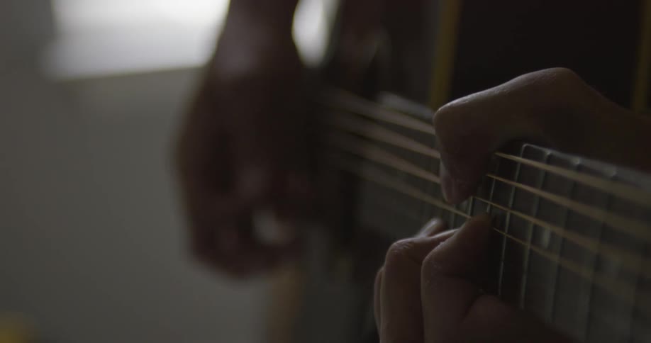 Man strums a guitar with a pick