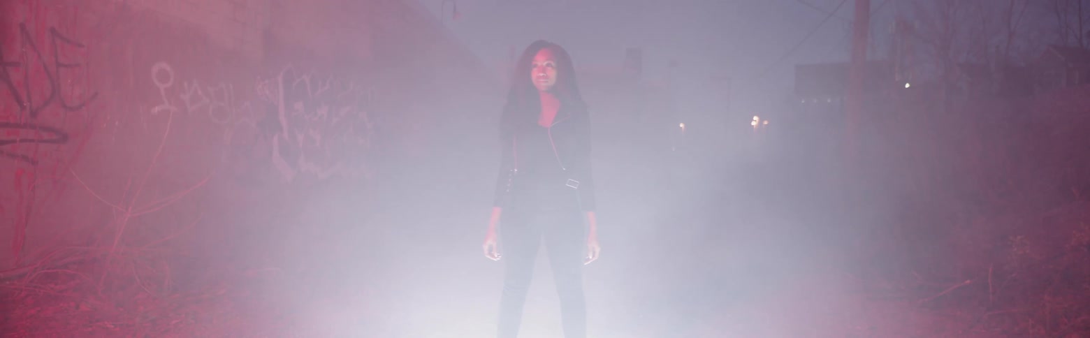 Woman stands in a dimly lit room surrounded by smoke