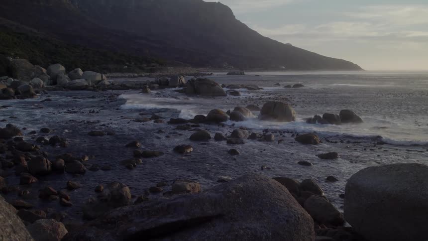 Small waves crashing against a rocky beach in the evening