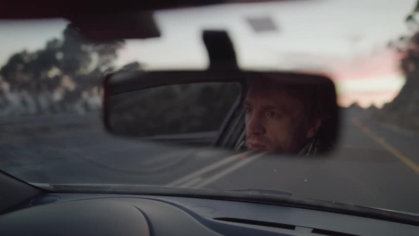 Man drives down the highway under a cloudy sky