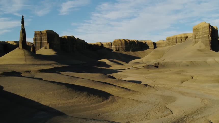 Shadows are creeping across the floor of a desert canyon during the day