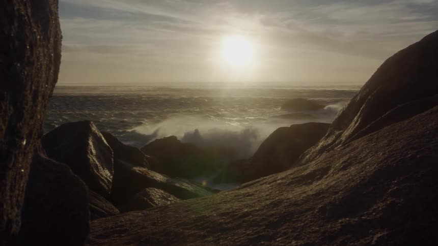 The waves crash on the rocks at sunset