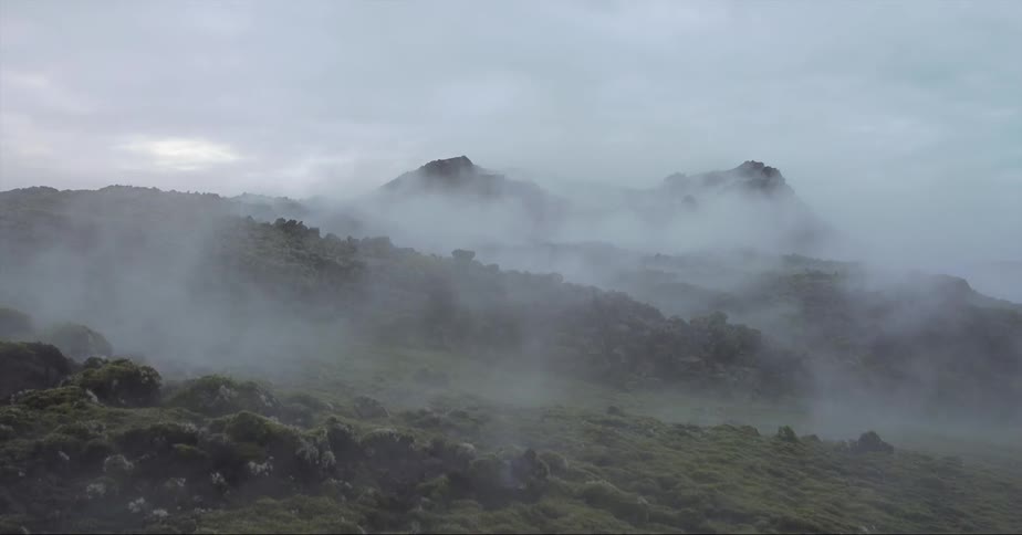 Fog rolls over peaks and green hills