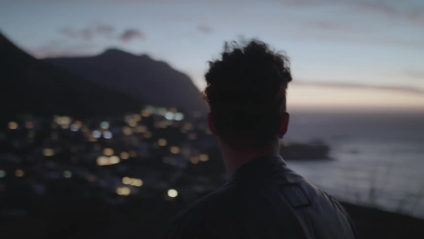 A man looks to the side at sunset on a windy day