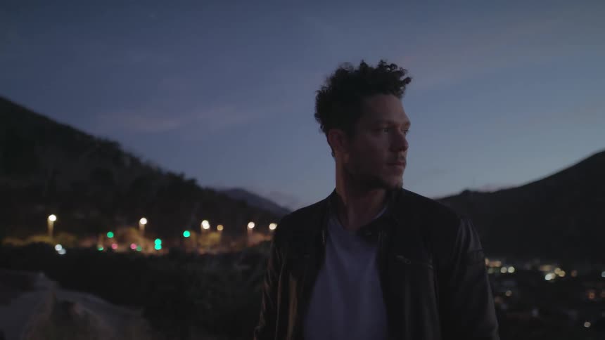 A man stands outside at dusk