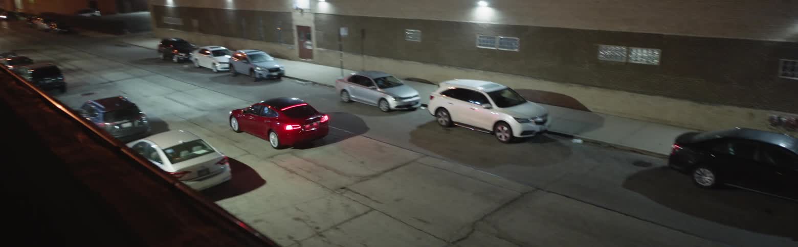 Red car driving down a city street very fast at night