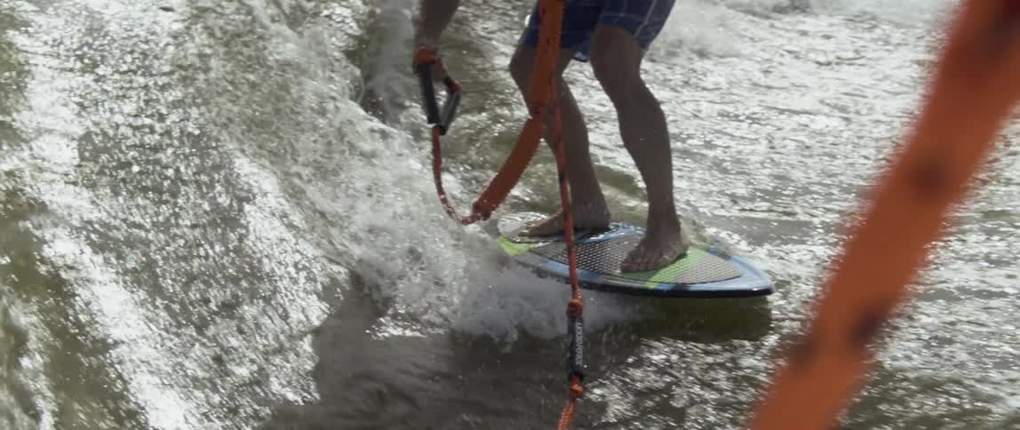 A man rides on a surfboard being pulled by a boat