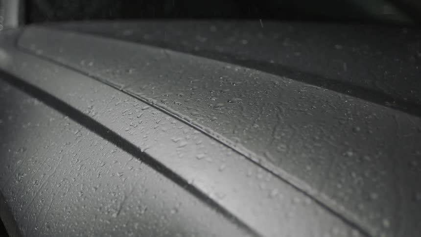 Rain falls and drips on a car