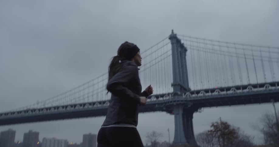 Woman jogs in the city near the river and a bridge