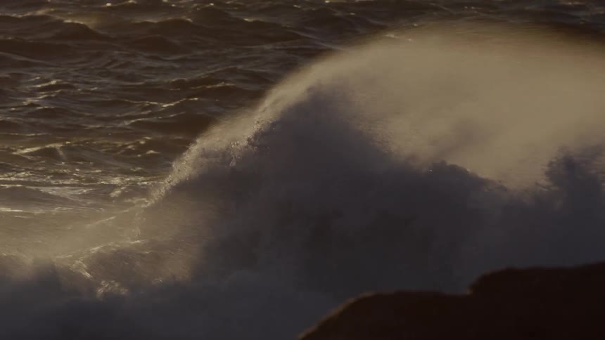 Water misting and splashing up on rocks at sunset