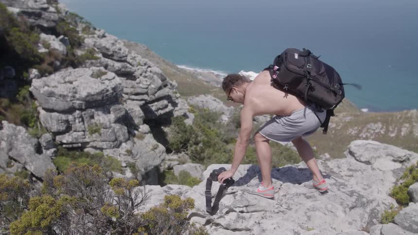 A man puts his camera down onto a rock