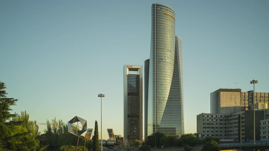 Tall skyscraper surrounded by trees near a busy road