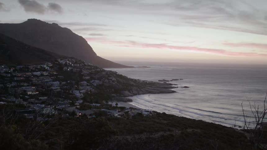 Sun sets over a city next to a beach