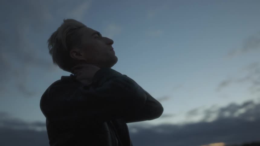 Man looks up outside at sunset