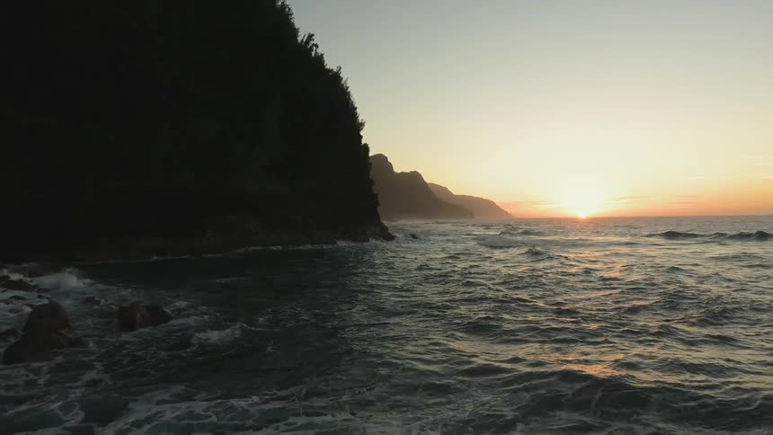 The water is very rough near the hills at sunset