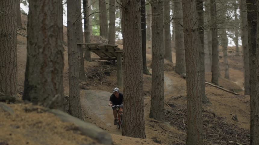 Man jumping off a ramp on his bike riding through the forest