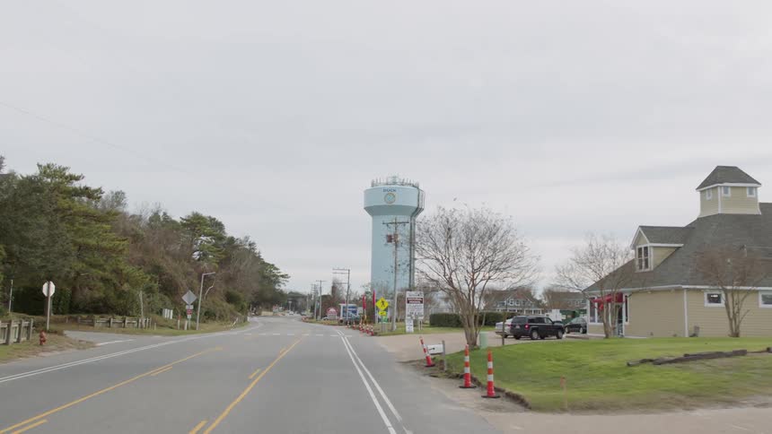 A road through a rural town with shops and a water tower
