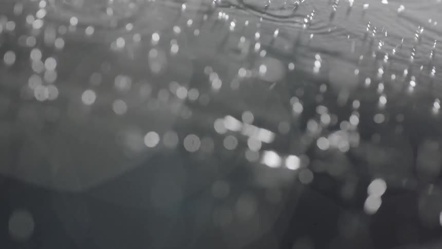 Water illuminated by light sprinkles down onto a shiny surface