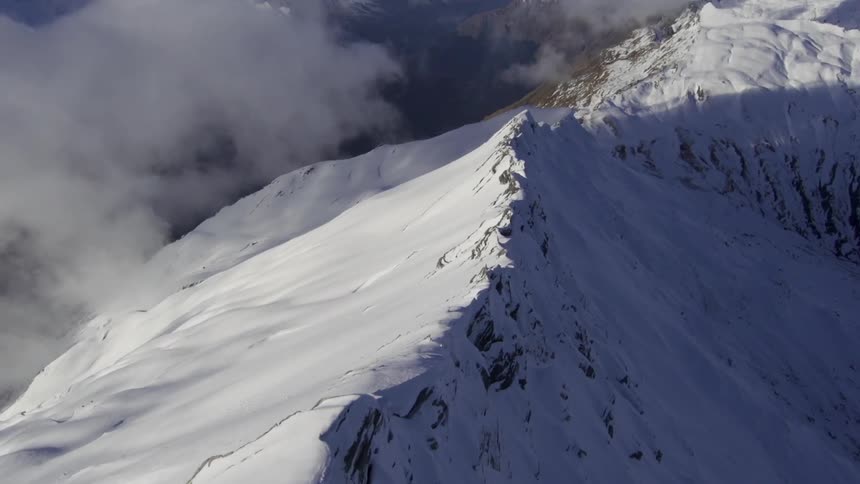 A snow capped mountain ridge in the clouds