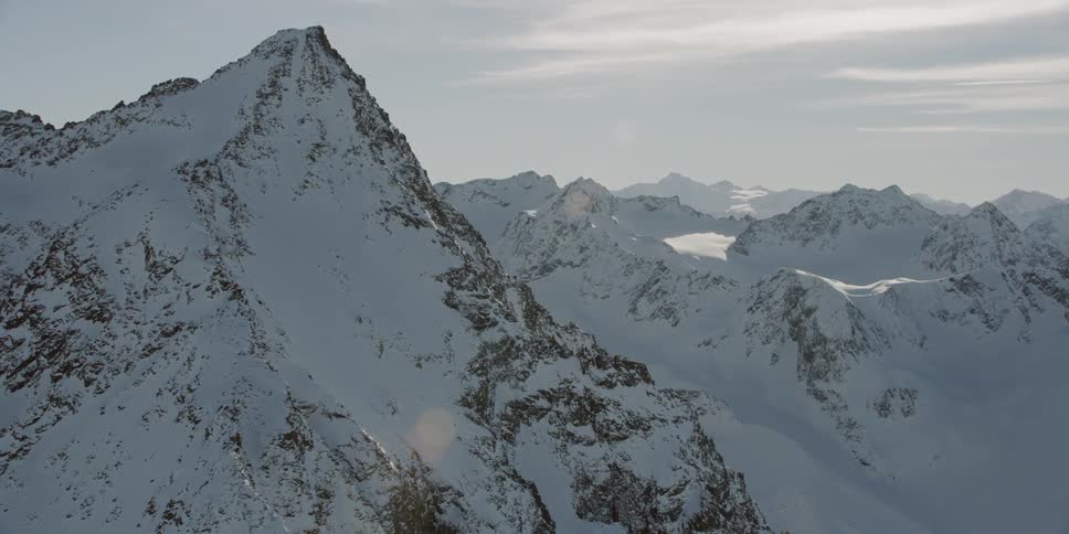 Sun shines over a large snowy mountain range