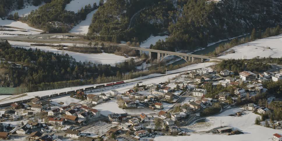A train is passing through a mountain village on a winter day