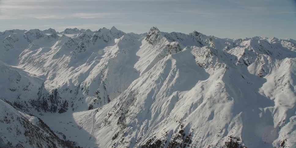 Large snowy mountain range with sun shining overhead
