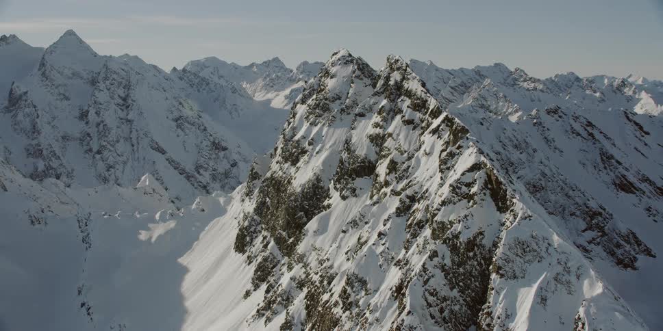 Sun shines down over snowy rocky mountain range