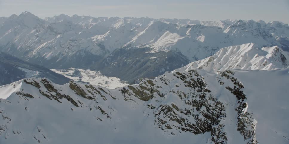 Sun shines down over a large snowy mountain range
