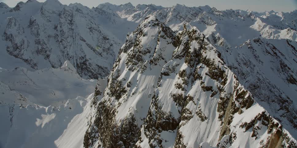 Sun shines down over large snowy mountain range