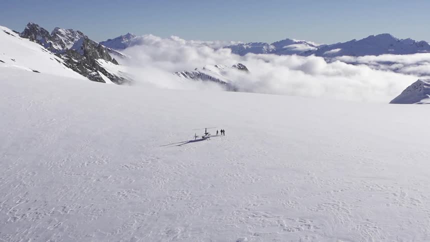 People standing near a helicopter on a snow covered mountain