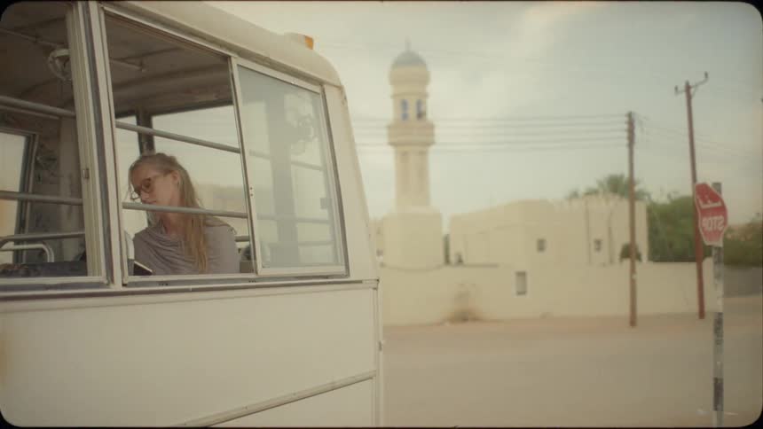 Woman sits in a small white bus in a foreign city