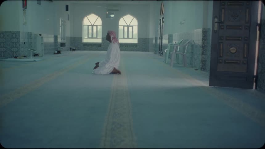 Man kneels on the floor in a large room