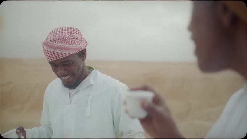 Two arab men are talking and drinking outside on a cloudy day
