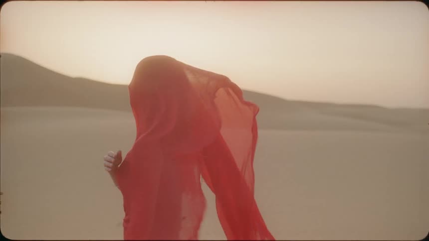 A red scarf blows on the face of a woman