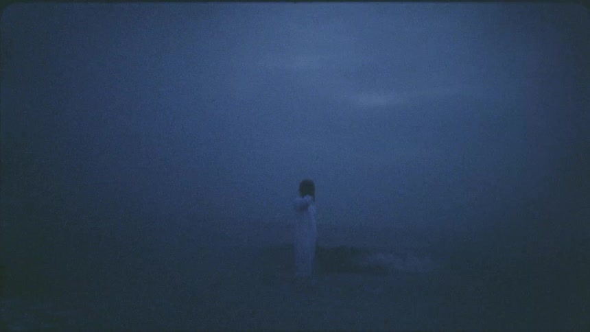 A clothed man stands in the waves