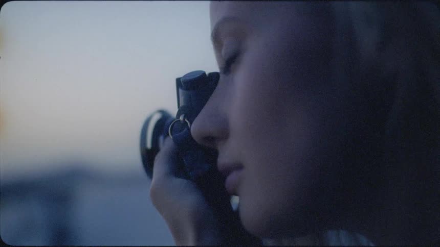 A woman holds up her camera and takes a photo at sunset