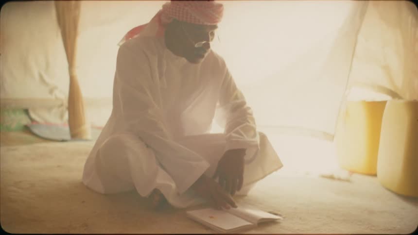 A middle eastern man reads from a book