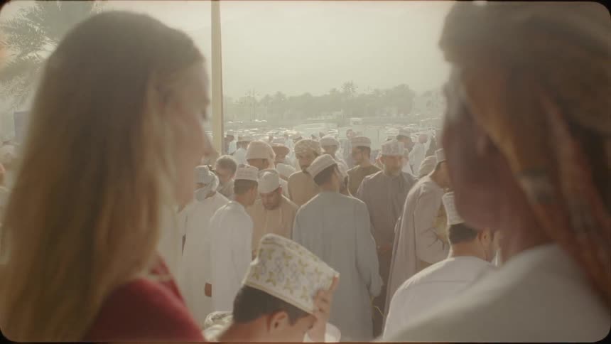 Woman talks to a man near a crowd of people in a city