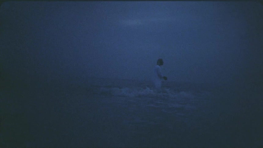 Person stands in the ocean as he washes his face