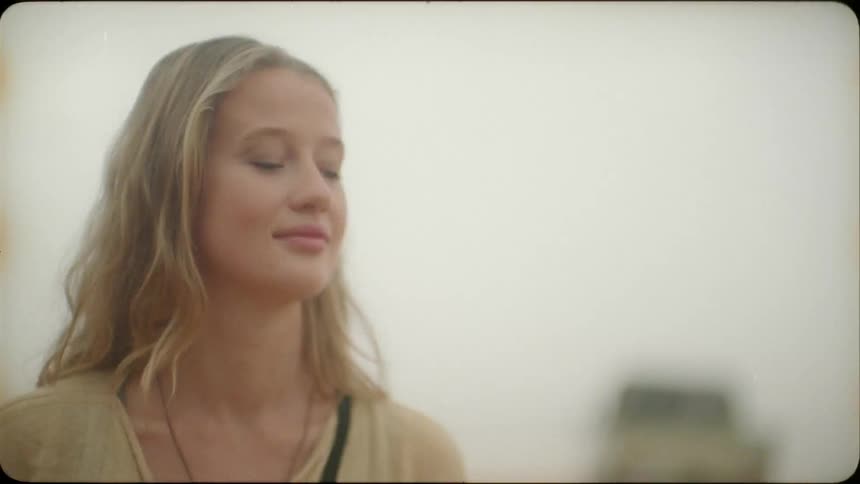 A blond haired woman smiles outside