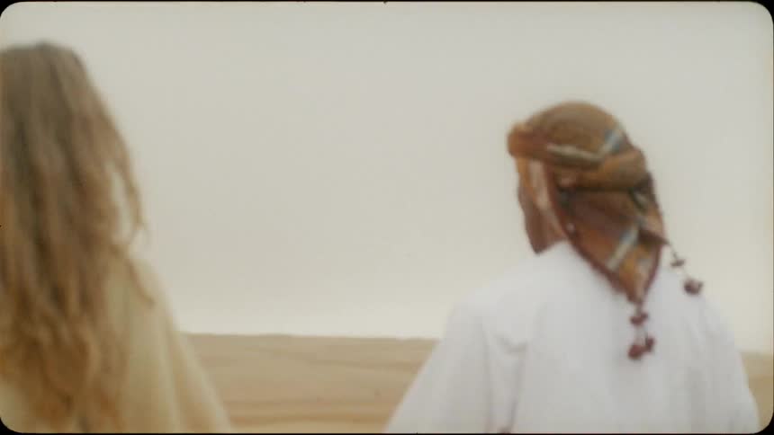 A man and woman walk together in the desert