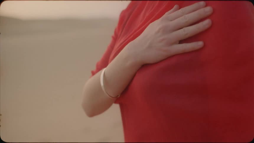 A woman touches her shoulder in the strong winds