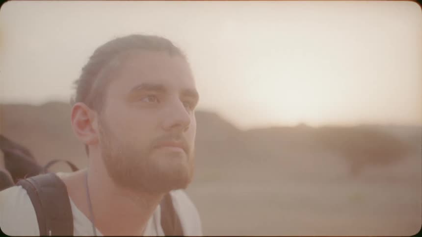 A man holding a camera up lowers it as he looks at the landscape