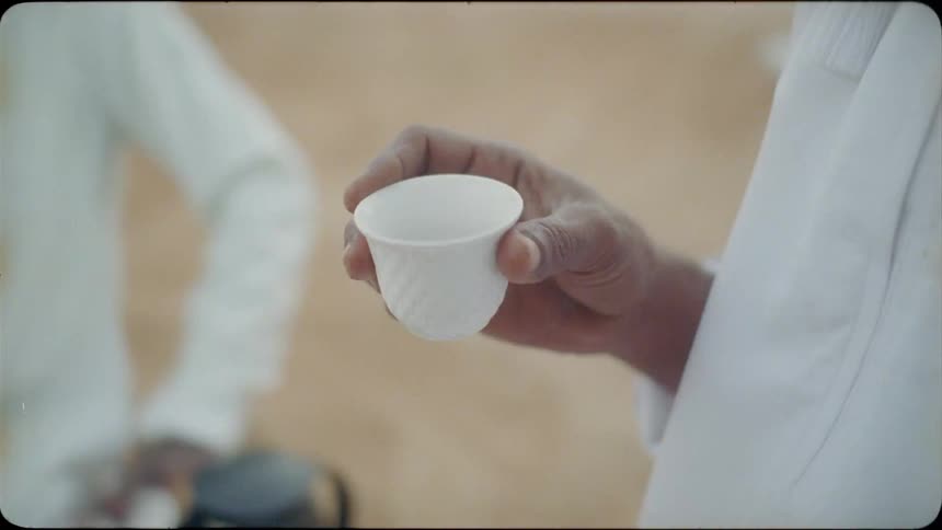 A man holds a cup outside