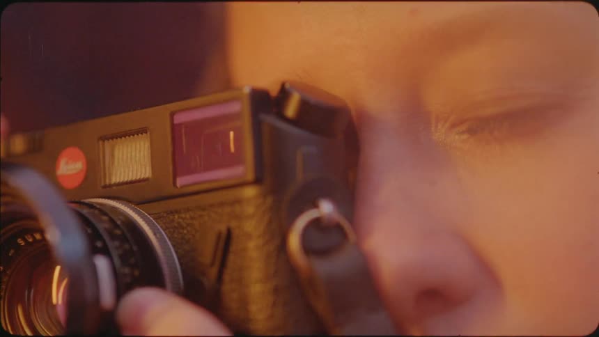 A woman focuses her camera and takes a photo by firelight